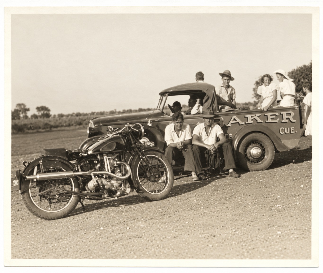 Group gathered beside the Cue bakery delivery truck and motorcycle
